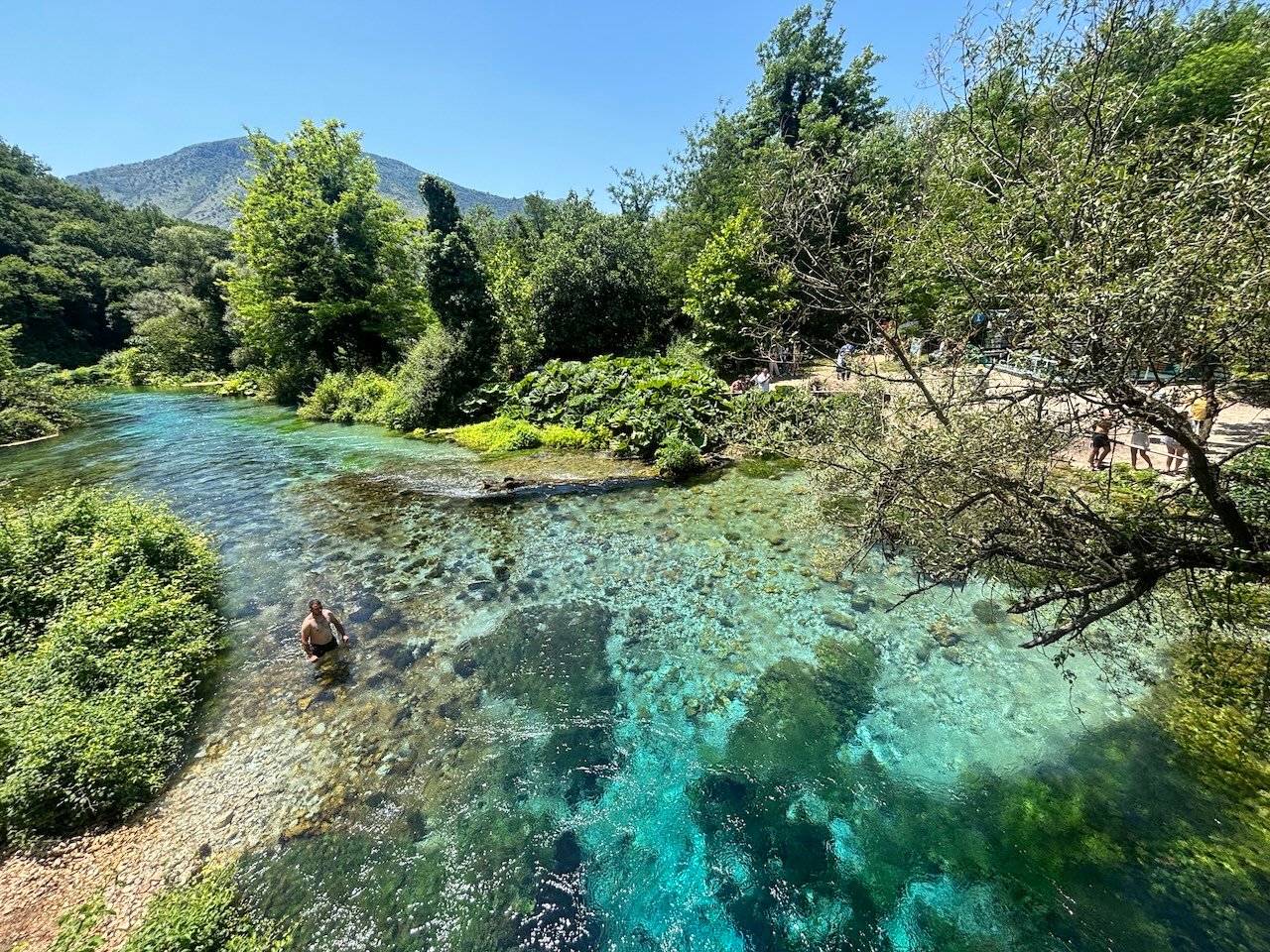 Occhio Blu in Albania con acqua cristallina, vegetazione e montagne sullo sfondo